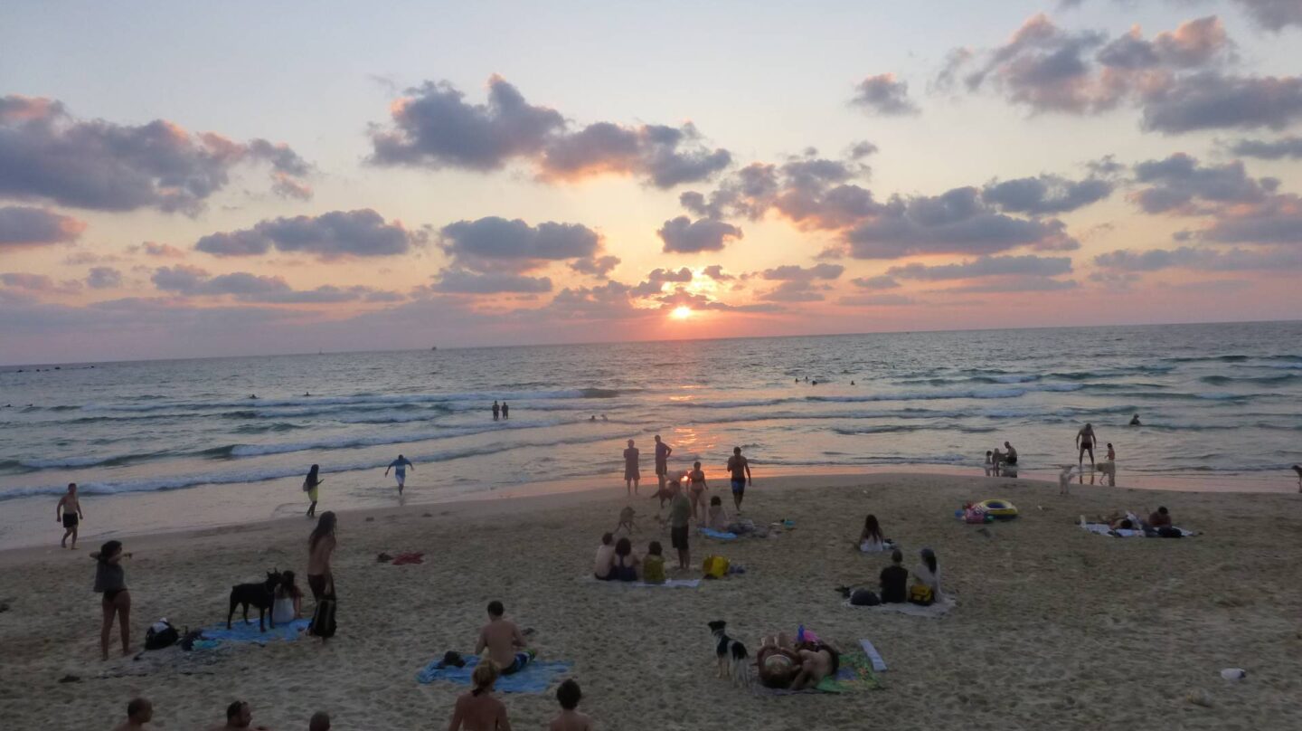 Varias personas disfrutan del atardecer en la playa.