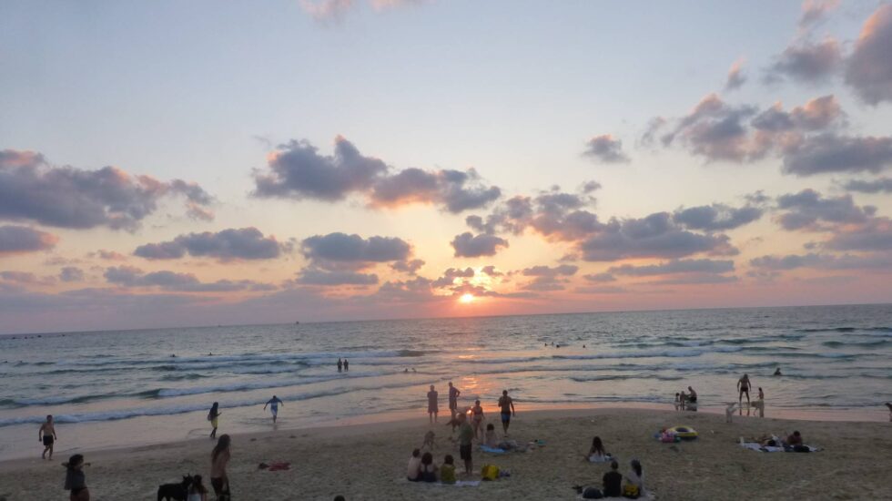 Varias personas disfrutan del atardecer en la playa.