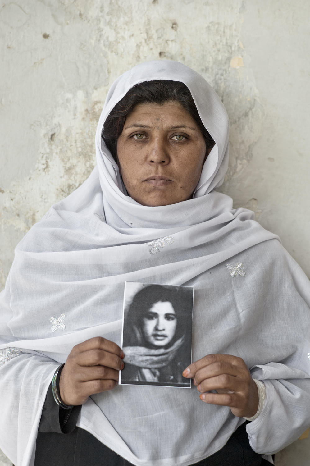 Nazanin, mujer afgana con burka que muestra la imagen de su hermano, víctima de la guerra.