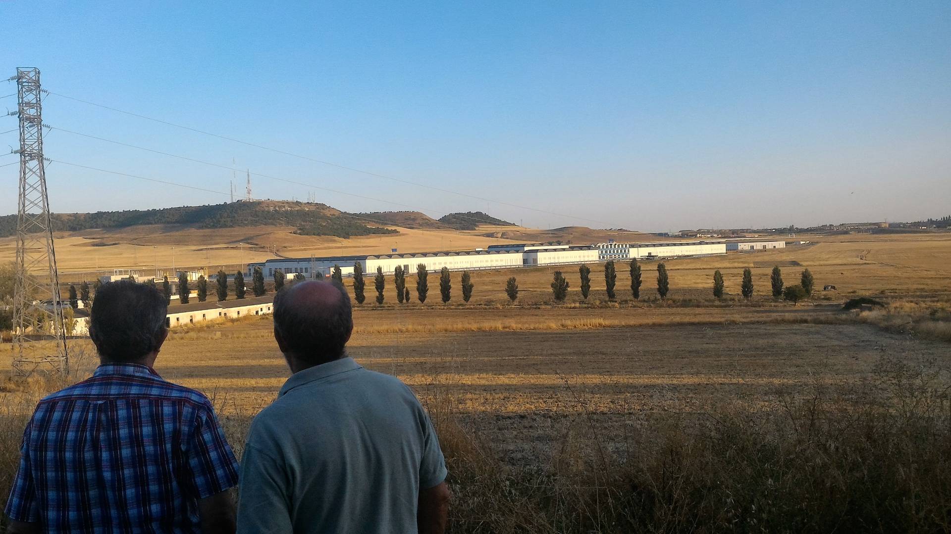 Dos hombres contemplan la Base de Mantenimiento Integral de Renfe desde un alto, en Valladolid. 