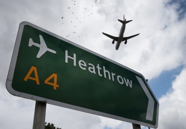 Un avión pasa sobre un indicador del aeropuerto de Heathrow, en Londres.