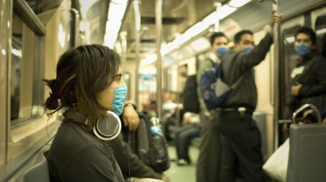 Los pasajeros viajan en el metro con mascarilla para evitar el contagio de la gripe.