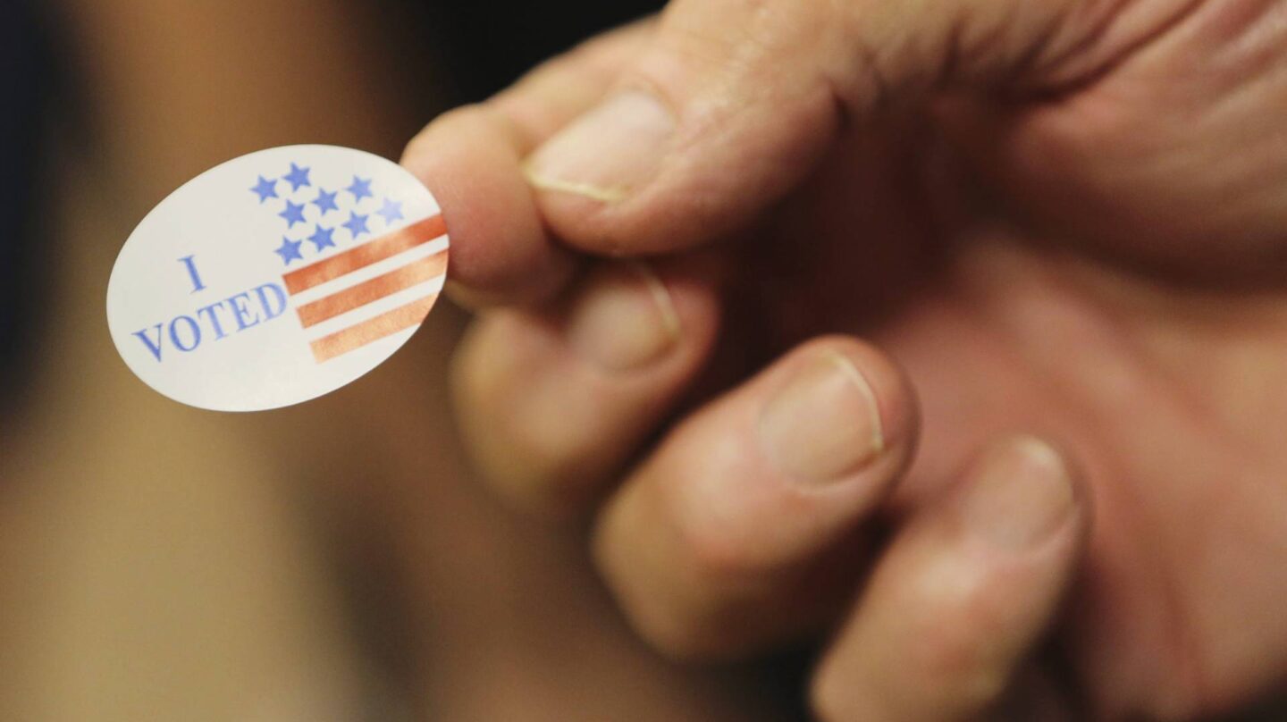 Un voluntario entrega una pegatina a los votantes durante las elecciones presidenciales en un centro electoral de Biloxi, Mississippi. EFE