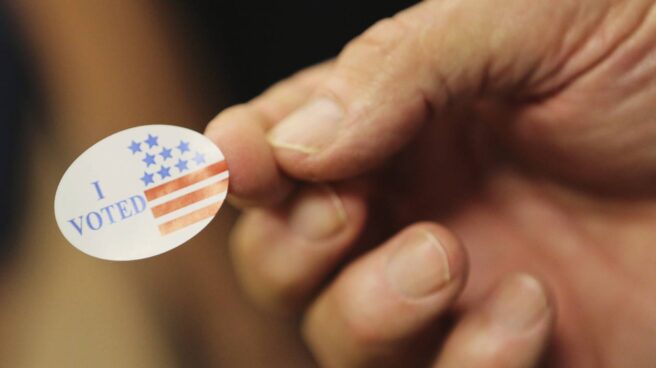 Un voluntario entrega una pegatina a los votantes durante las elecciones presidenciales en un centro electoral de Biloxi, Mississippi. EFE