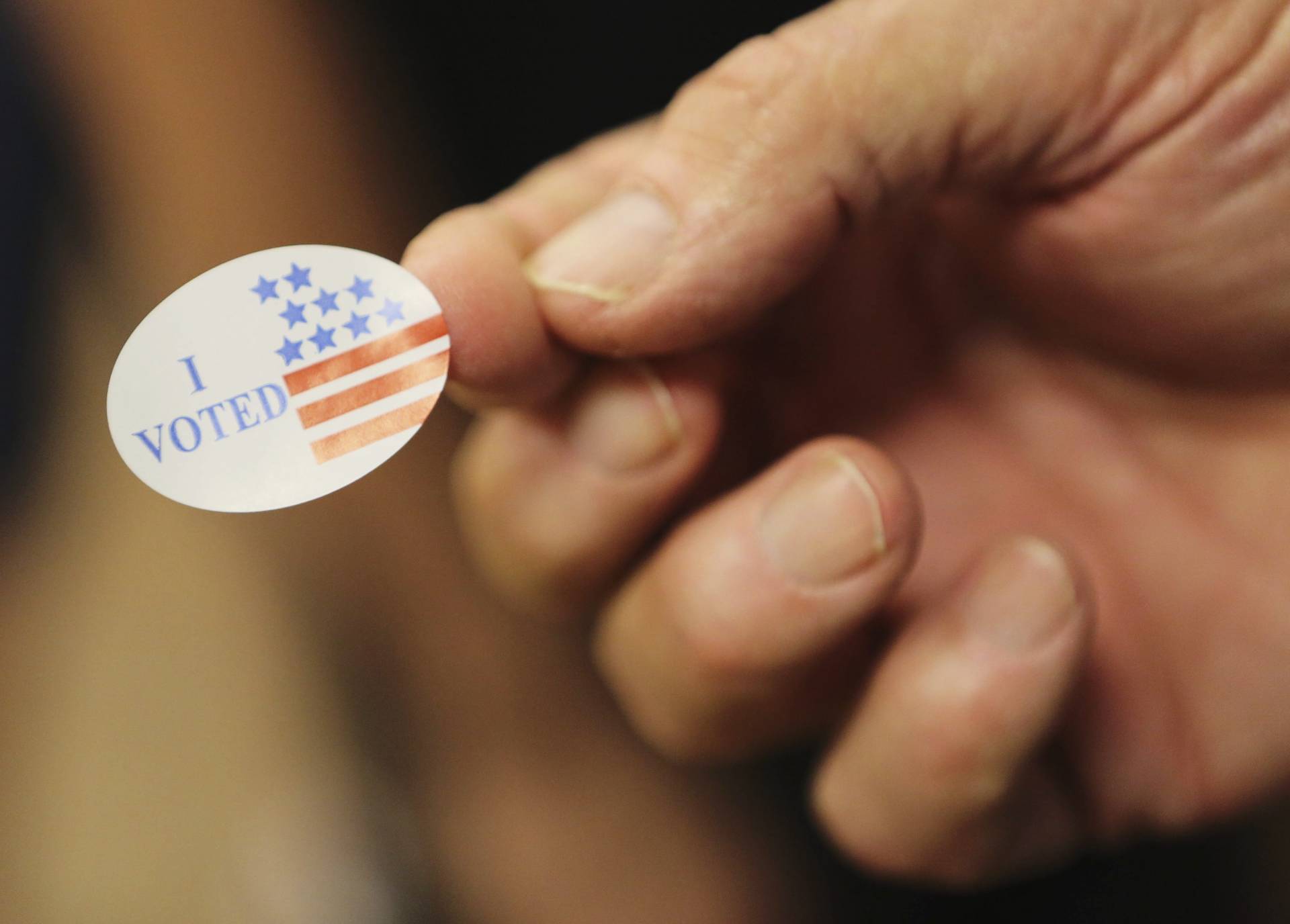 Un voluntario entrega una pegatina a los votantes durante las elecciones presidenciales en un centro electoral de Biloxi, Mississippi. EFE