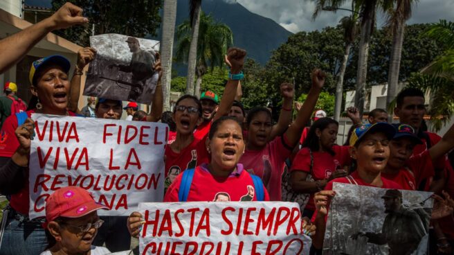 Un grupo de personas gritan consignas mientras hace fila para firmar un libro de condolencias por la muerte del líder cubano.