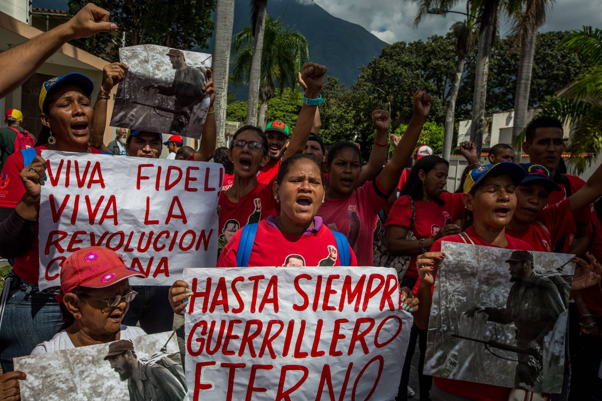 Un grupo de personas gritan consignas mientras hace fila para firmar un libro de condolencias por la muerte del líder cubano.