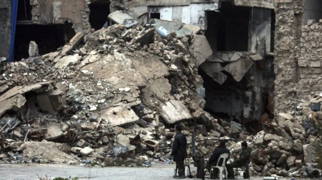 Un grupo de personas contemplan un edificio de Alepo en ruinas.