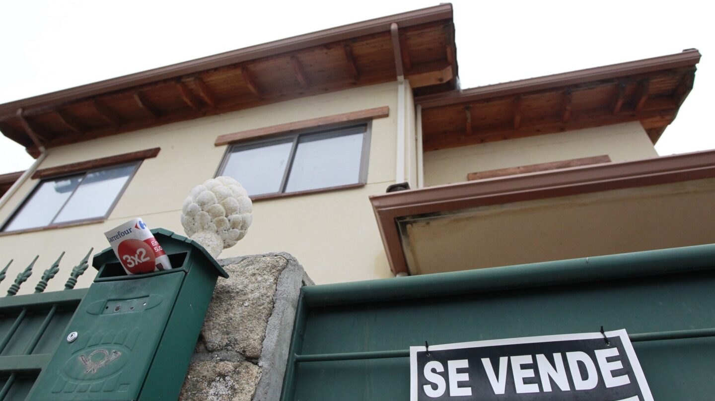 Una vivienda con un cartel de "se vende" en su fachada.