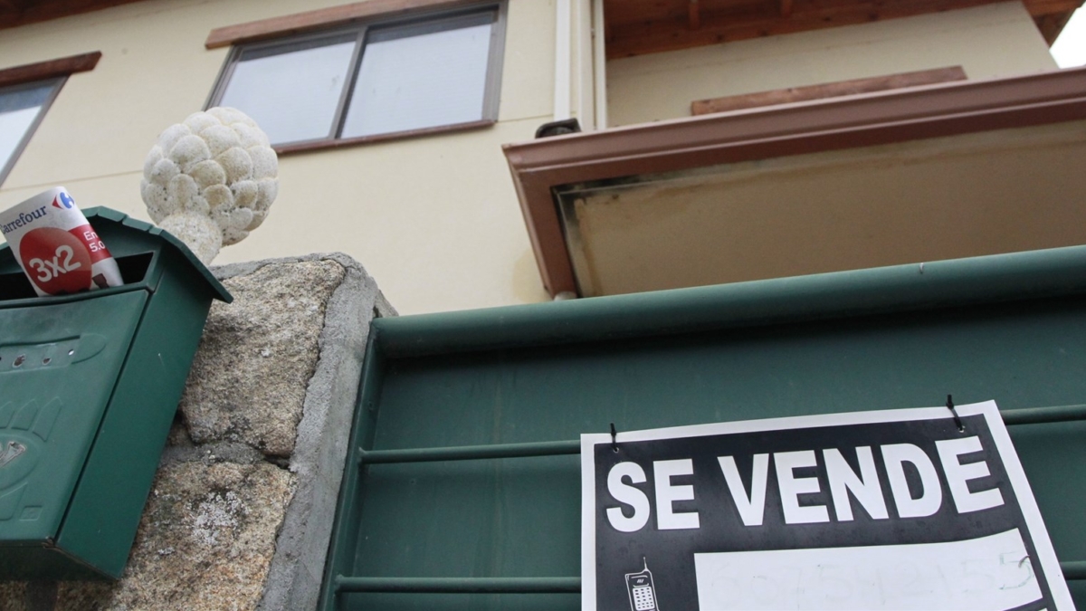 Una vivienda con un cartel de "se vende" en su fachada.