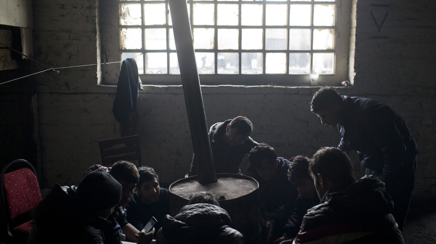 Refugiados de Afghanistan se calientan con un tambor de aceite en un almacén abandonado en Belgrado, Serbia.