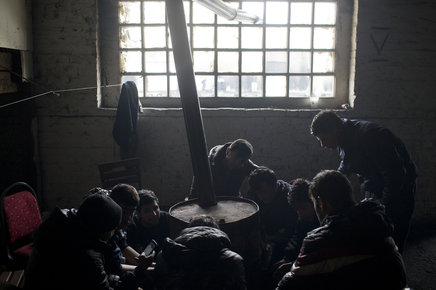 Refugiados de Afghanistan se calientan con un tambor de aceite en un almacén abandonado en Belgrado, Serbia.