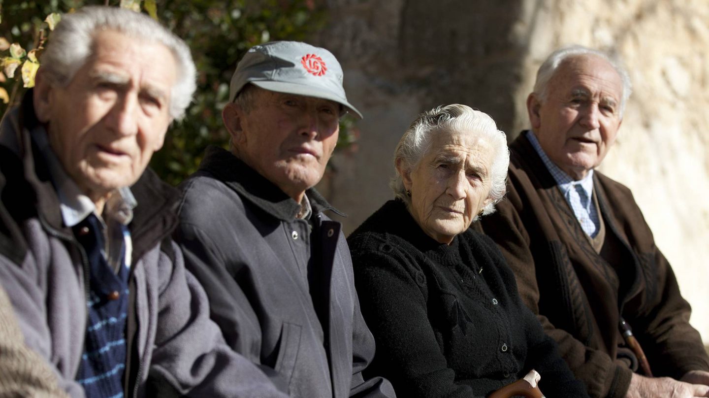 Ancianos sentados en una plaza pública.