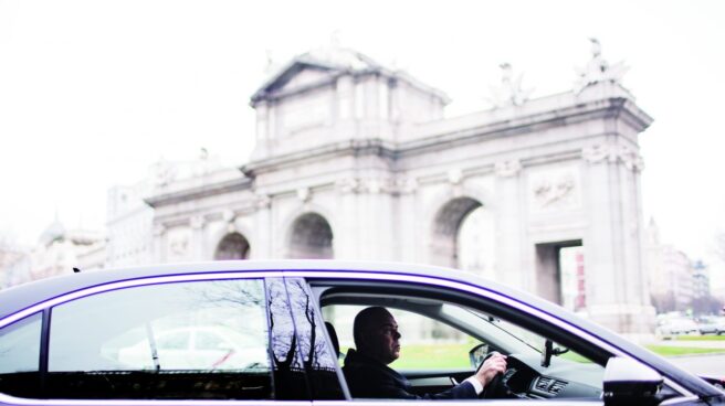 Un coche de Uber, circulando por la Puerta de Alcalá en Madrid.