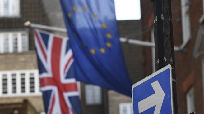 Una bandera europa ondea junto a la británica en una calle de Londres, junto a un indicativo de salida.