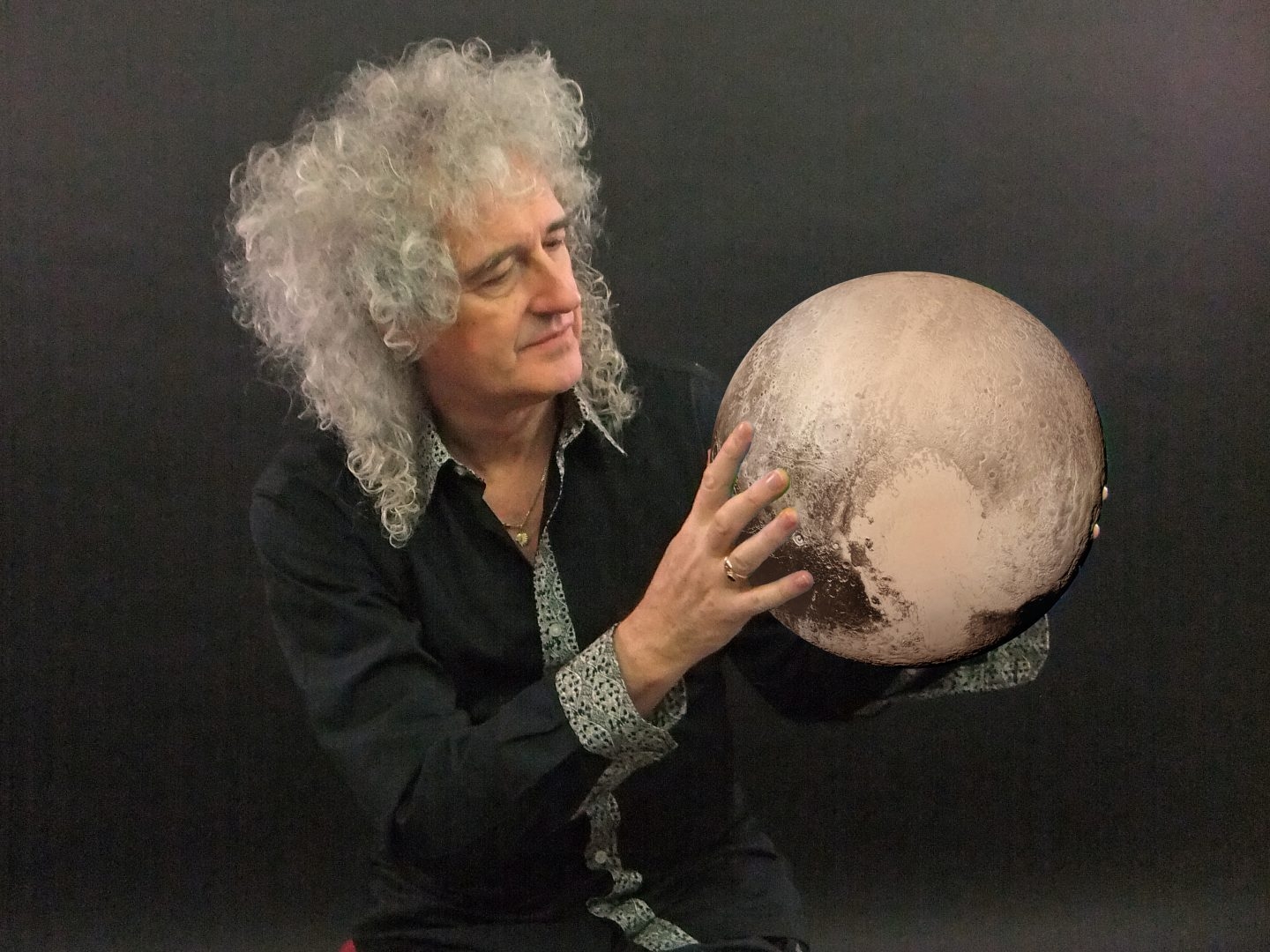 Brian May, guitarrista de Queen y astrofisico, con Plutón 