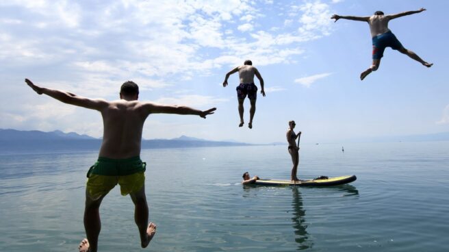 Varias personas disfrutan del buen tiempo en el lago de Lemán en frente de los Alpes.
