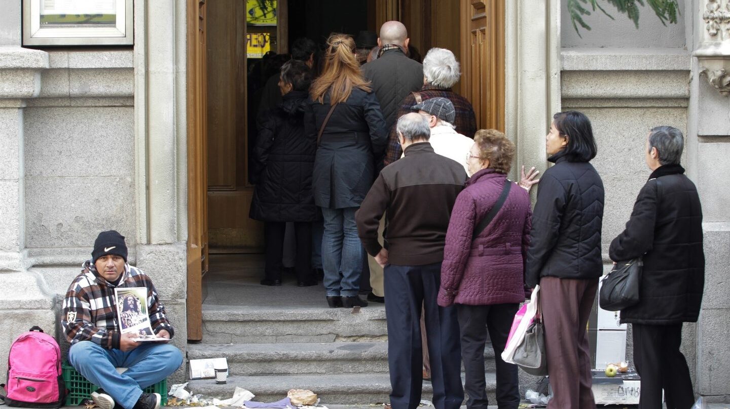 Pobre pidiendo en la puerta de un edificio.