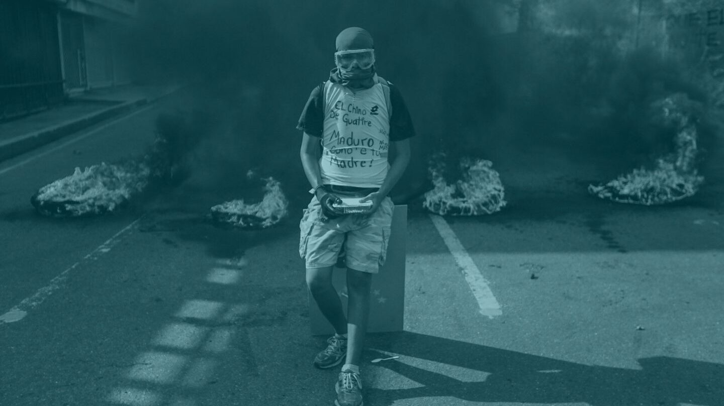 Un manifestante permanece en frente de una barricada en llamas durante una manifestación en Venezuela.