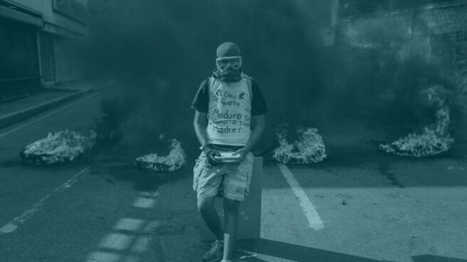 Un manifestante permanece en frente de una barricada en llamas durante una manifestación en Venezuela.