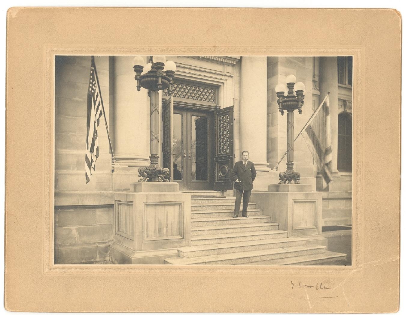 Retrato de Joaquín Sorolla Bastida en la escalinata de entrada al edificio de La Hispanic Society of America de Nueva York, engalanada con las banderas de España y de los Estados Unidos, probablemente el día de la inauguración de la exposición monográfica del artista.