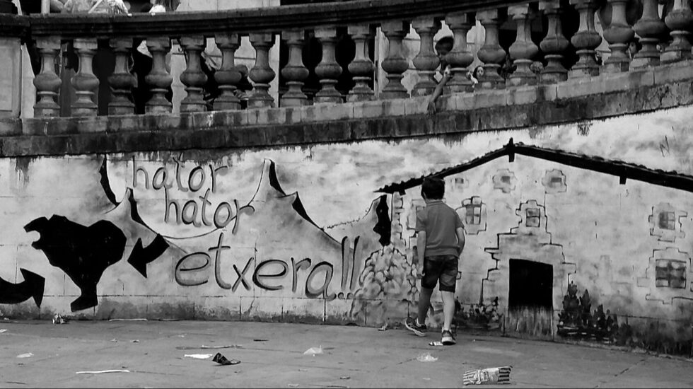 Dos niños juegan junto a un mural que reclama la vuelta de los presos de ETA a casa.