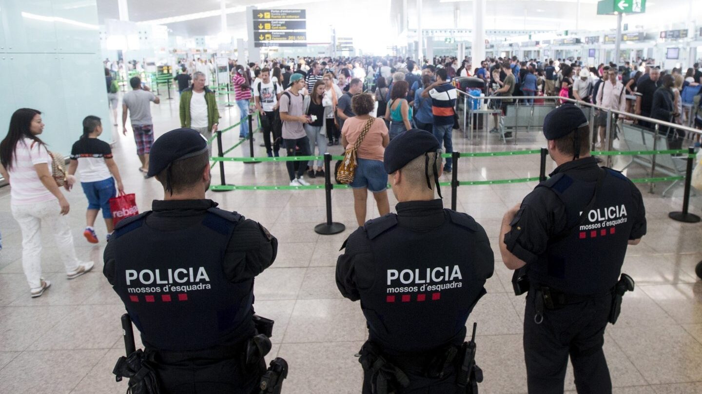 Tres mossos vigilan a los pasajeros en El Prat.