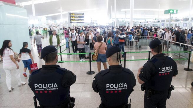 Tres mossos vigilan a los pasajeros en El Prat.