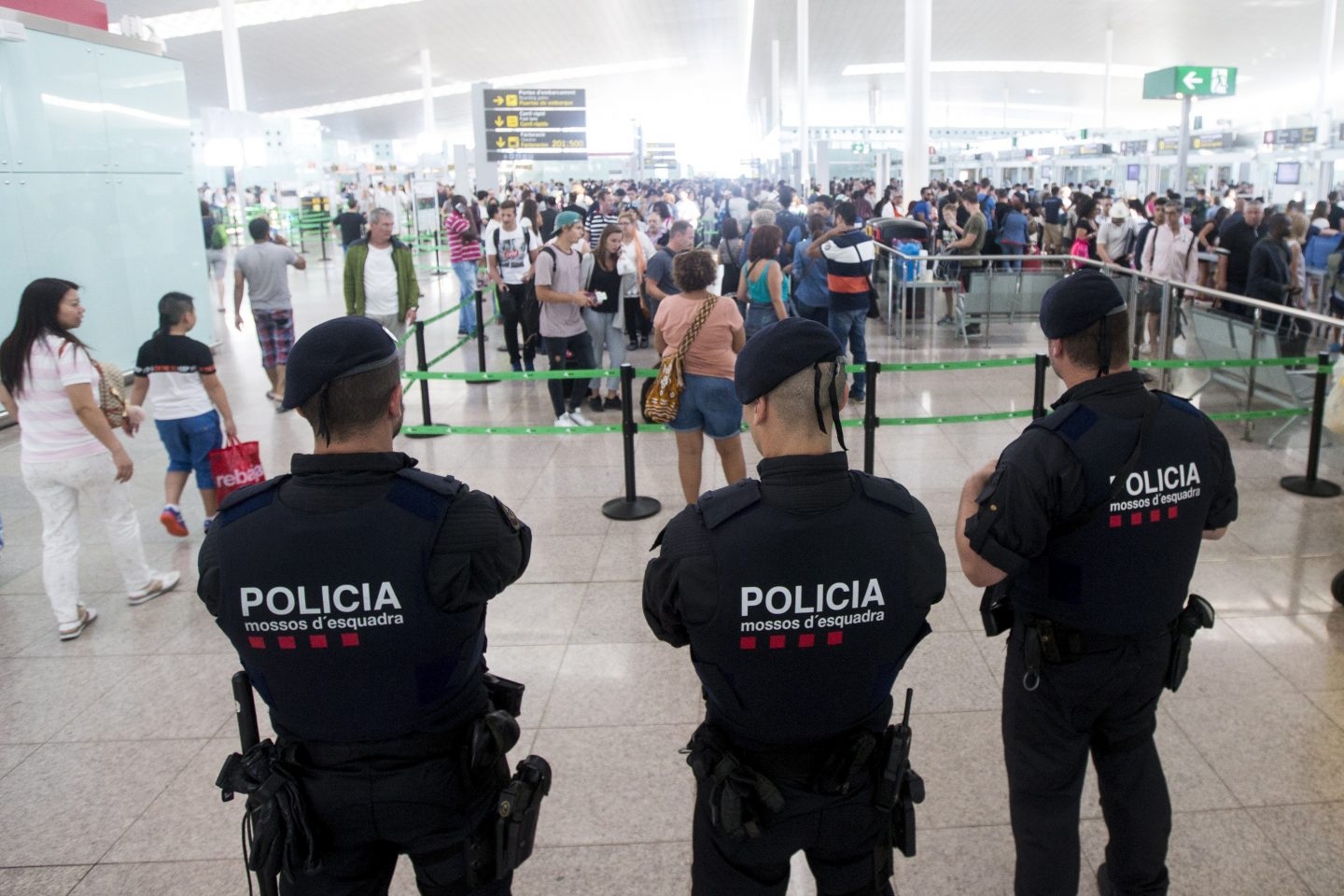 Tres mossos vigilan a los pasajeros en El Prat.