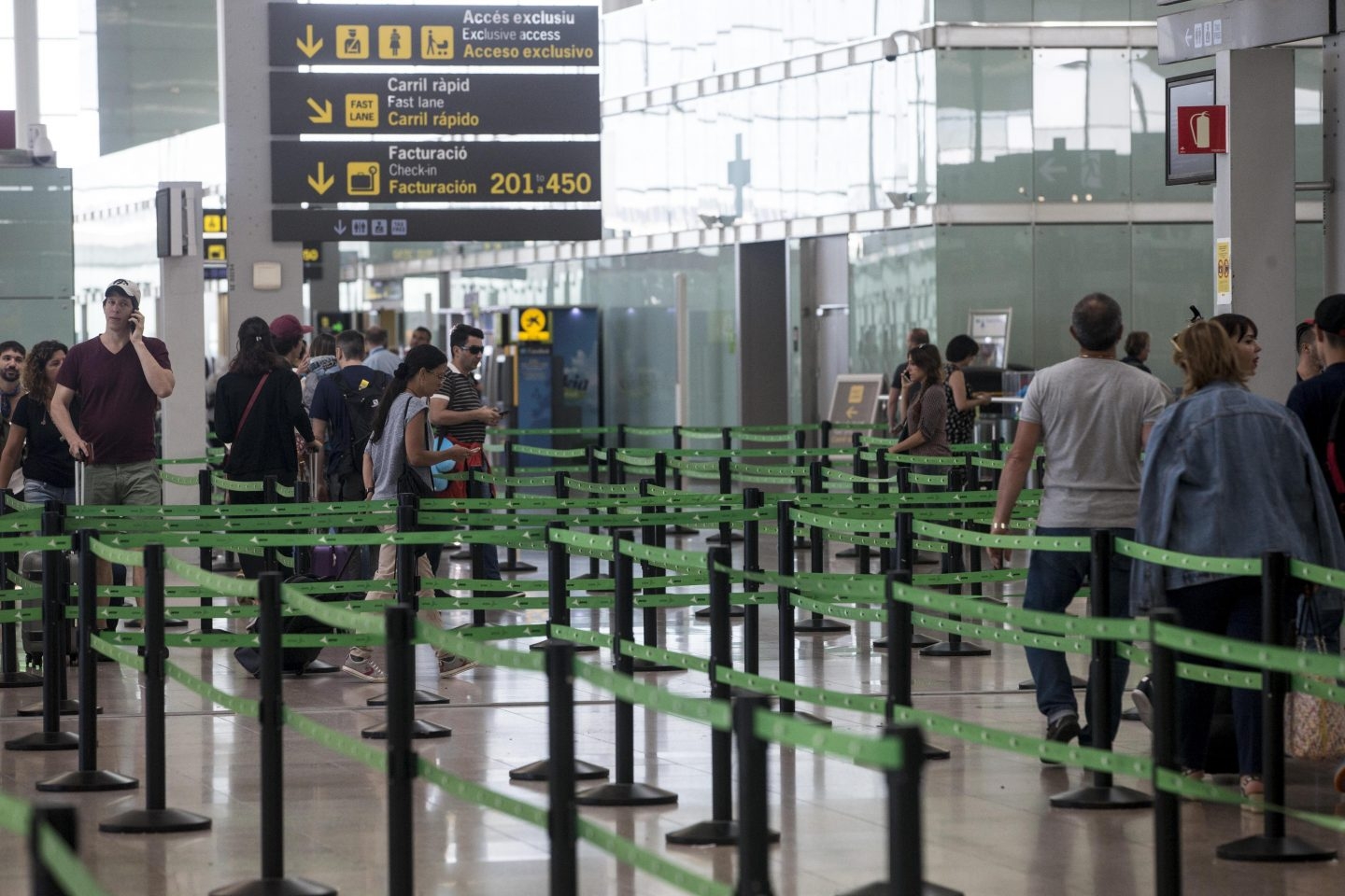 Pasajeros esperan ante el arco de seguridad en El Prat.