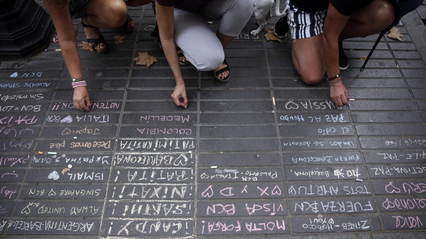 Varias personas escriben en mensajes en homenaje a las víctimas del atentado de Barcelona.
