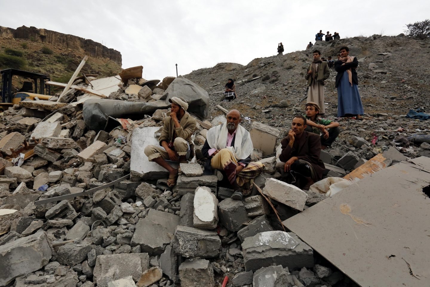 Varios yemeníes sentados entre los restos de un edificio tras un bombardeo de la coalición liderada por Arabia Saudí, en Saná.