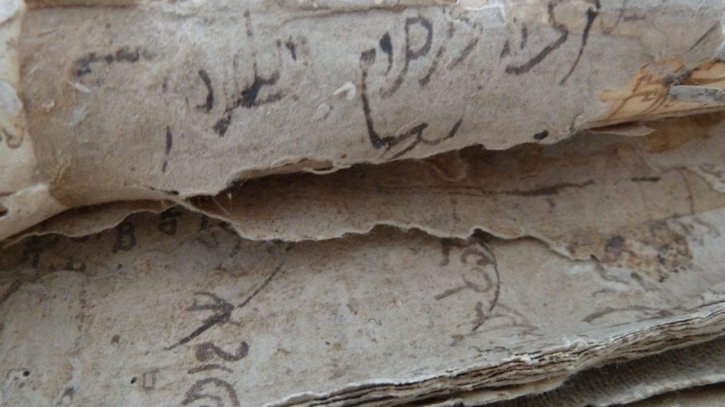 Detalle de varias capas de papel que forman el cartón oculto tras las cubiertas de piel que encuaderna el libro de cuentas manuscrito y que contienen escritura hebrea y latina (siglo XV)