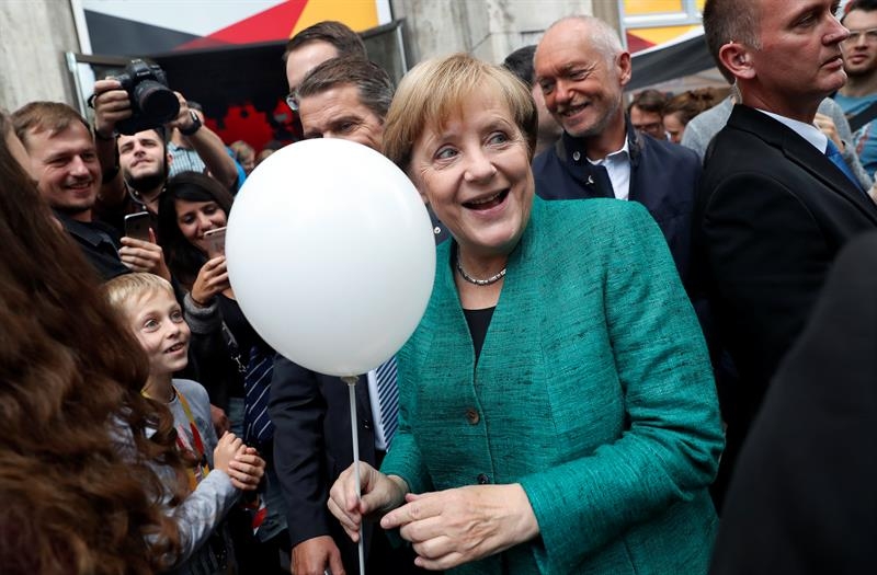 Angela Merkel recibe un globo de un niño en la campaña electoral en Berlín.