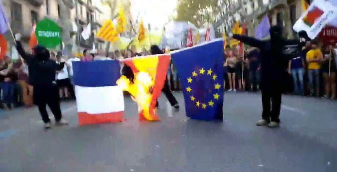 Tres encapuchados queman las banderas de Francia, España y la UE.