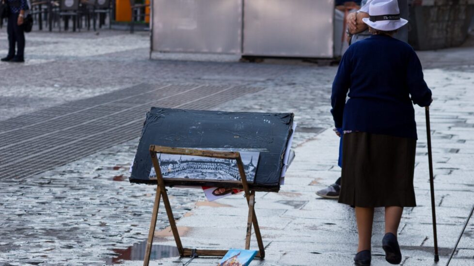 Una mujer pasea al lado de un puesto de arte.