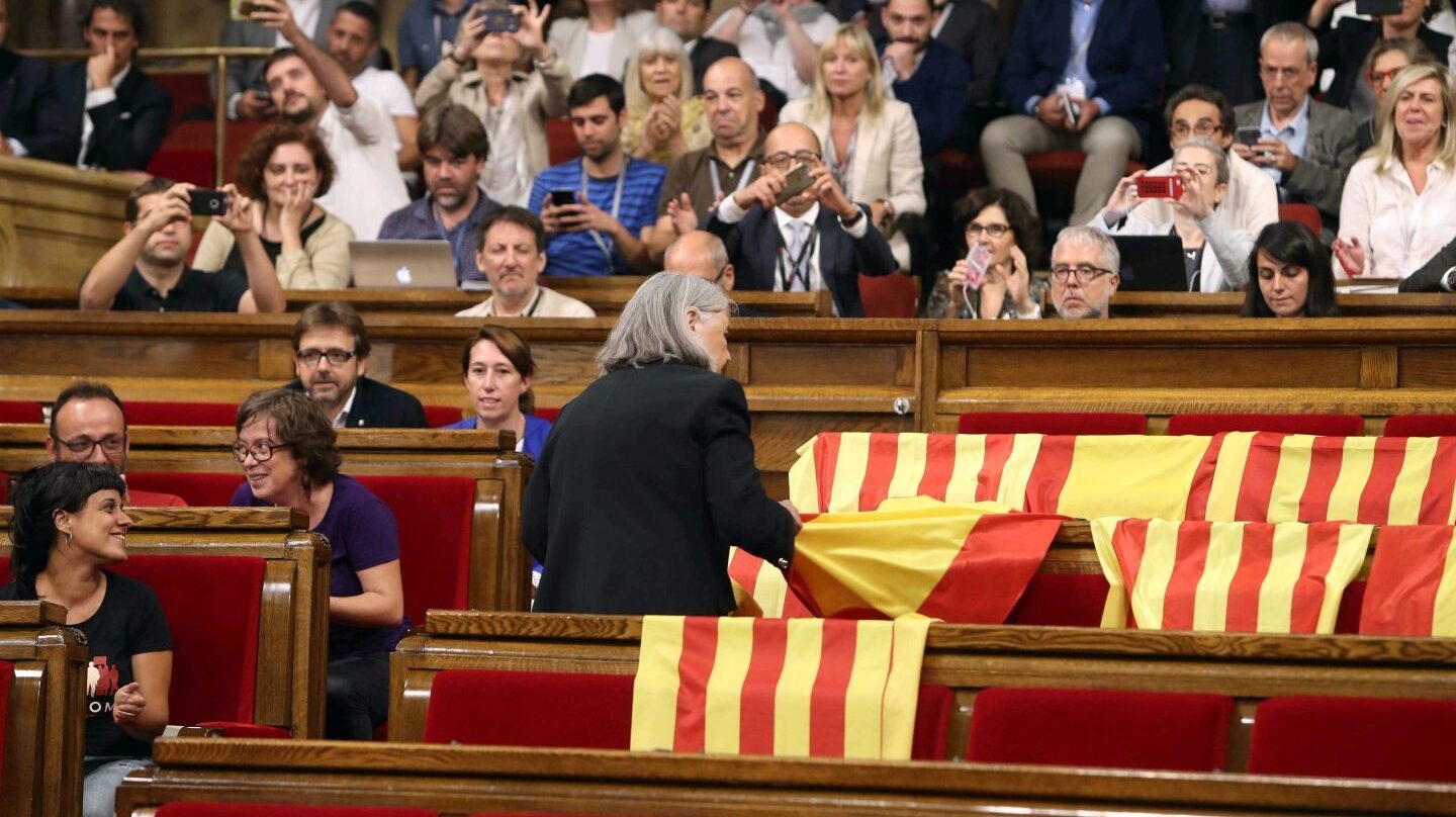 La diputada de Podem Ángels Martínez reitra las banderas de España del hemiciclo del Parlament y deja las esteladas catalanas.