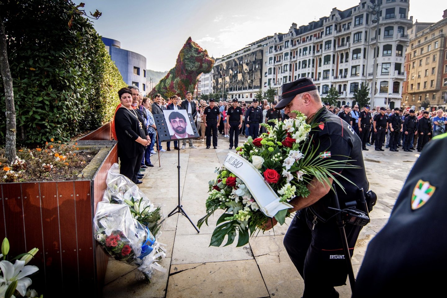 Agentes de la Ertzaintza ponen flores delante del monolito que hay en recuerdo de Txema Agirre.