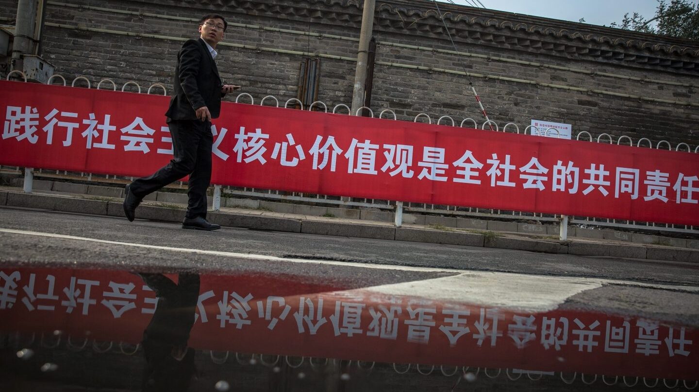 Un hombre pasa junto a una pancarta con propaganda del XIX Congreso del .Comunista de China