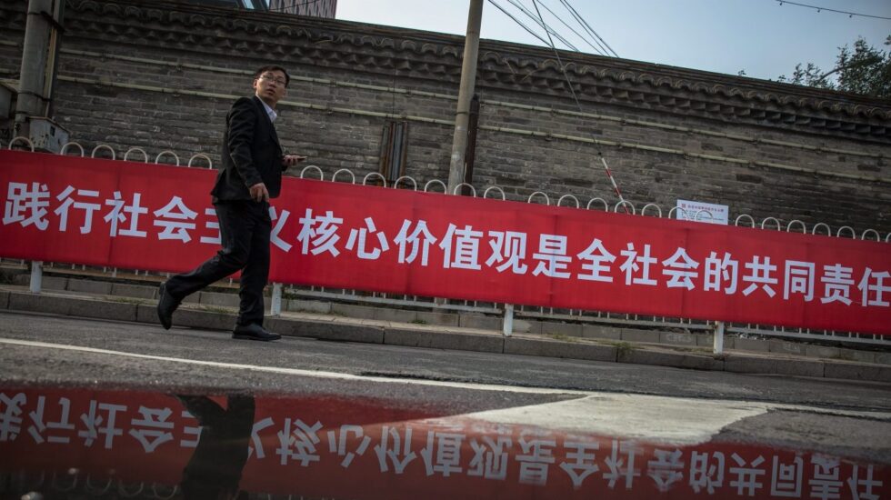 Un hombre pasa junto a una pancarta con propaganda del XIX Congreso del .Comunista de China