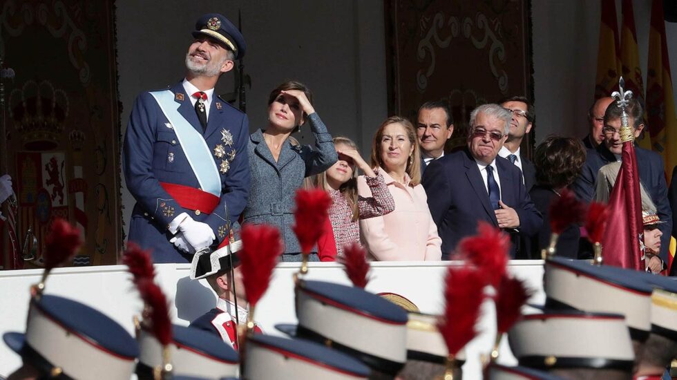 Los Reyes junto a sus hijas, observan el desfile aéreo, durante el acto del Día de la Fiesta Nacional al que asiste el Gobierno en pleno y la mayoría de líderes políticos.