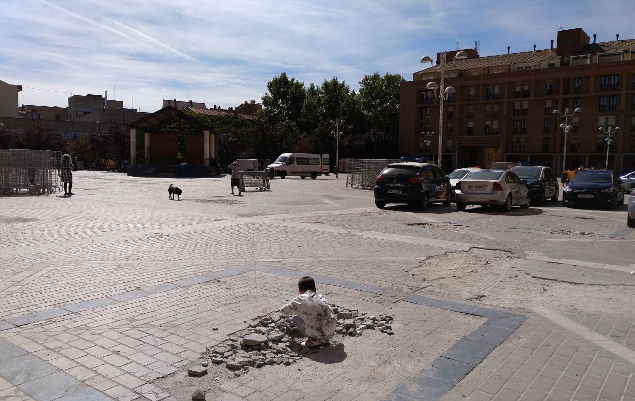 Un crío juega sobre los cascotes de un socavón en La Remonta. Junto a él, coches de policía aparcados de manera ilegal.