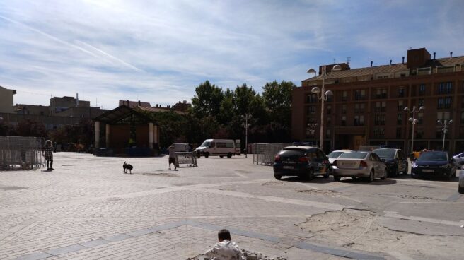 Un crío juega sobre los cascotes de un socavón en La Remonta. Junto a él, coches de policía aparcados de manera ilegal.