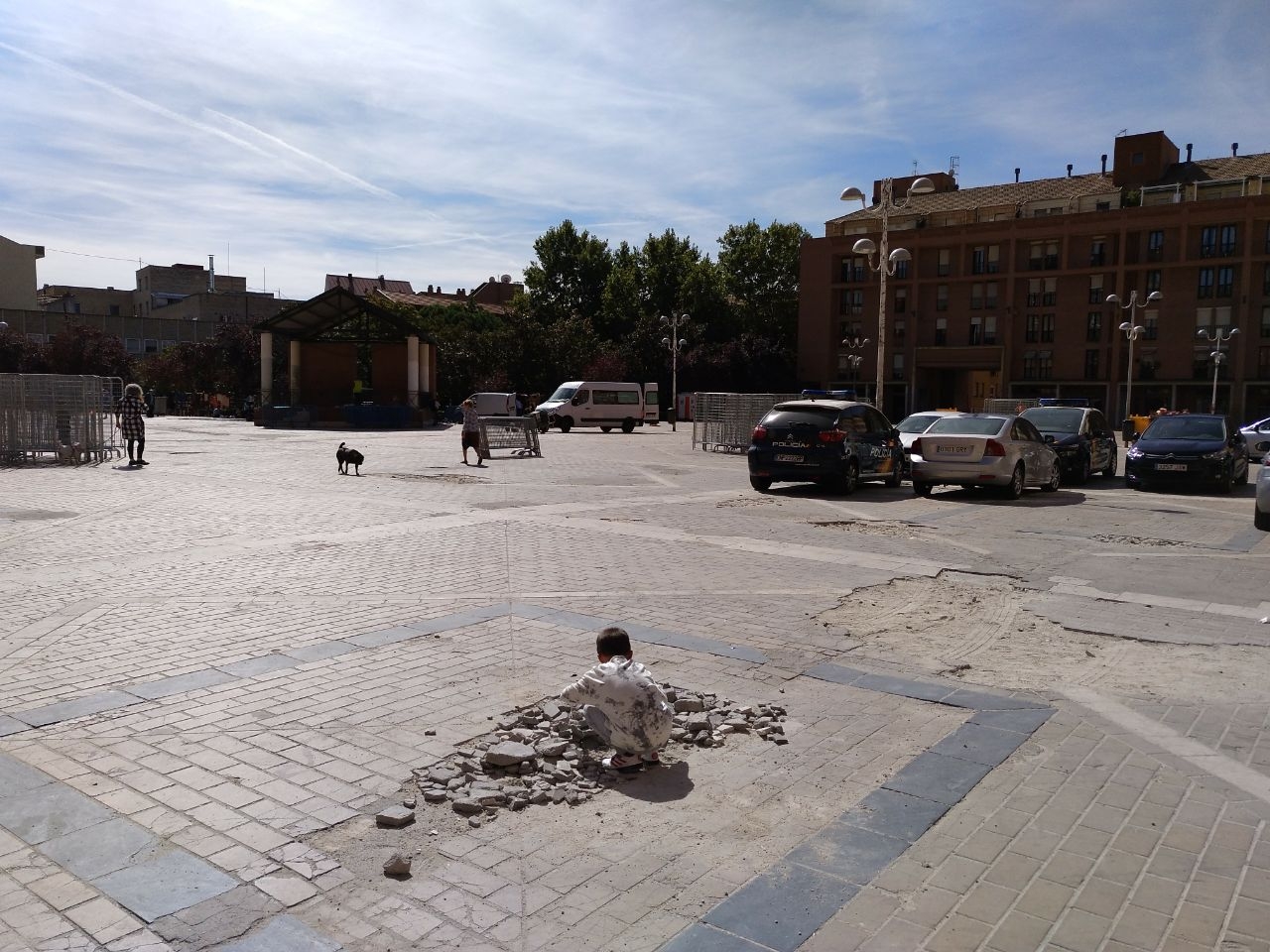 Un crío juega sobre los cascotes de un socavón en La Remonta. Junto a él, coches de policía aparcados de manera ilegal.