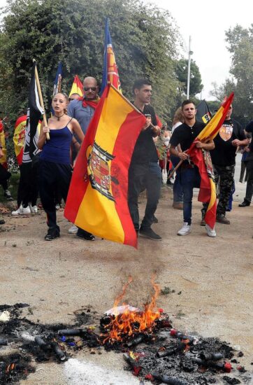 Colectivos de ultraderecha portan banderas preconstitucionales mientras queman banderas esteladas y propaganda independentista durante una manifestación en defensa de la unidad nacional en la plaza de Sant Jordi, en Barcelona.