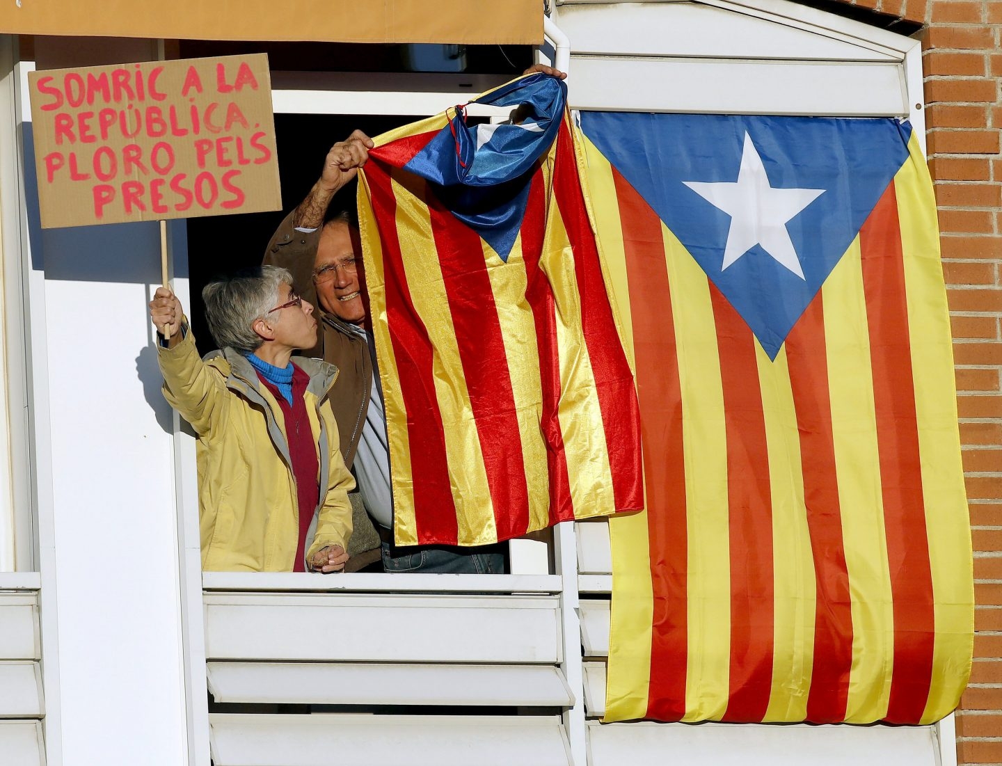 Un vecino saca una bandera "estelada" por la ventana durante la manifestación convocada en Barcelona por la ANC y Ómnium Cultural.