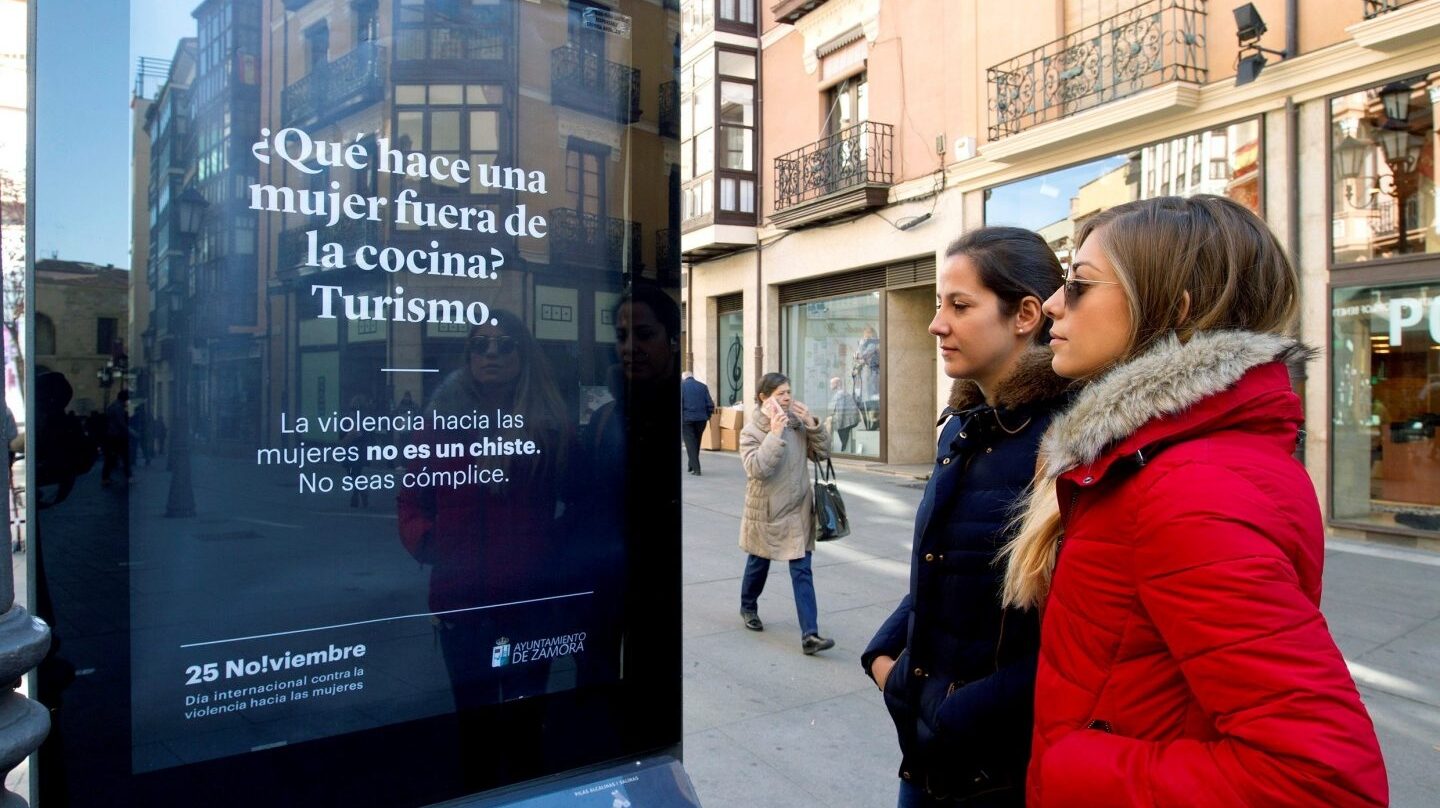 Dos mujeres contemplan un mupi con mensajes de la campaña contra la violencia de género en Zamora.