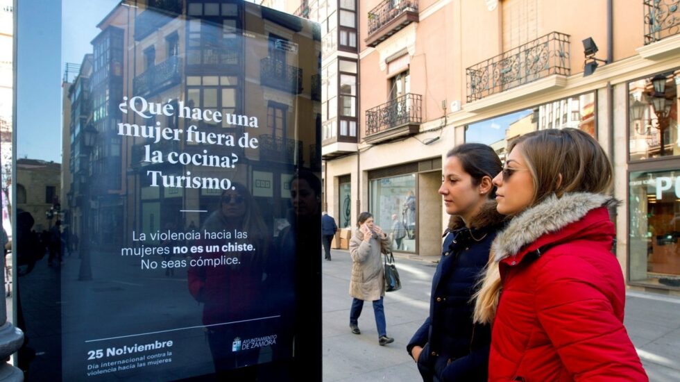 Dos mujeres contemplan un mupi con mensajes de la campaña contra la violencia de género en Zamora.