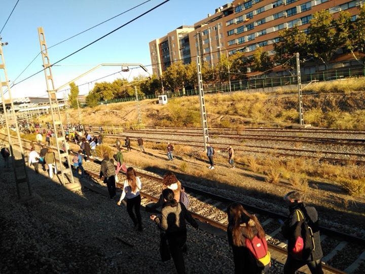 Pasajeros de un tren de Cercanías en Madrid caminan por las vías tras una avería.