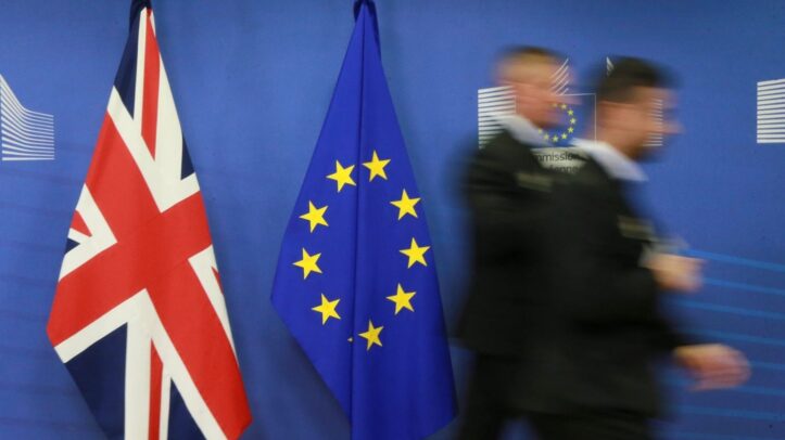 Dos empleados pasan junto a las banderas del Reino Unido y la Unión Europea.